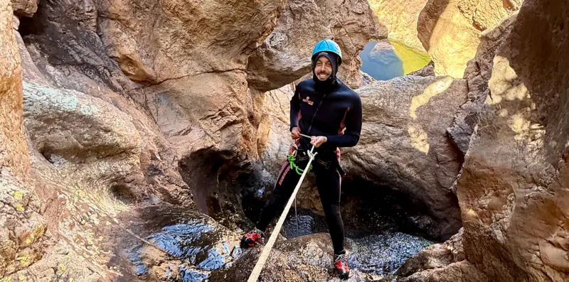 Un participant équipé descend en rappel dans un canyon de l’Anti-Atlas